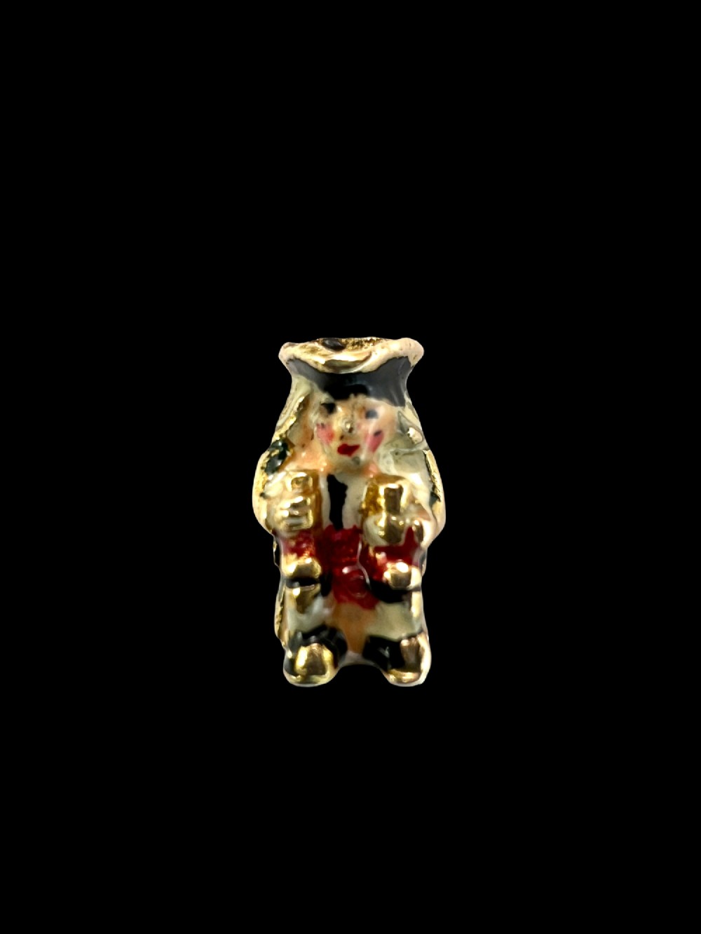 A miniature 9ct gold and enamel Toby jug charm depicting a seated figure in a tricorn hat with red and black painted details. View IX