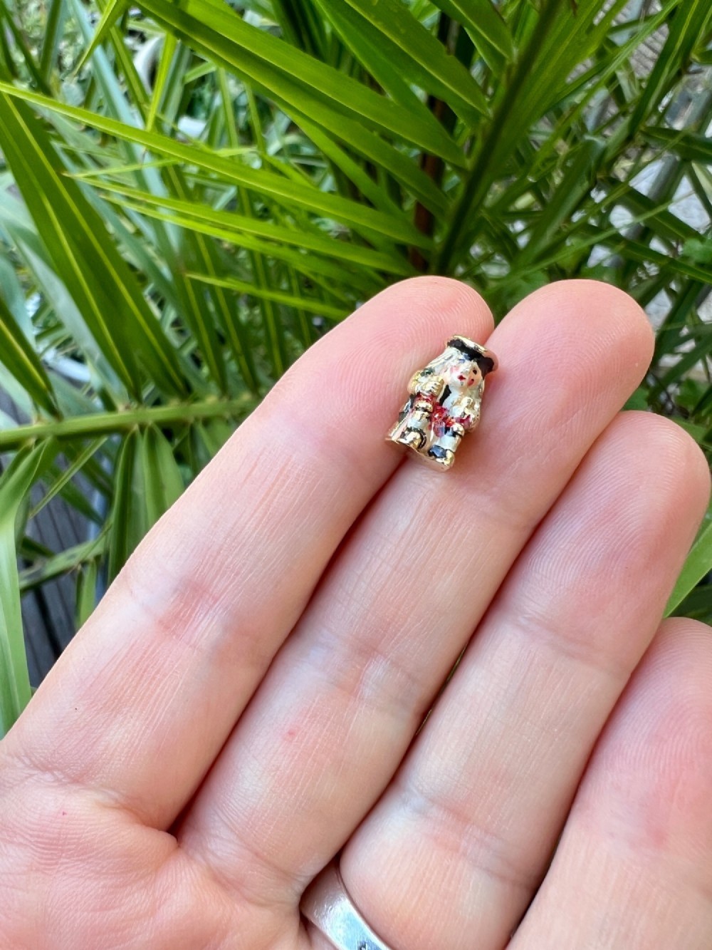 A miniature 9ct gold and enamel Toby jug charm depicting a seated figure in a tricorn hat with red and black painted details. View X
