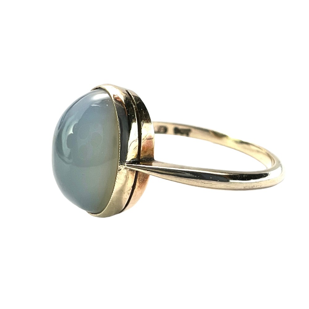An Edwardian 9ct yellow gold solitaire ring featuring a smooth, oval grey chalcedony cabochon set in a bezel mount.