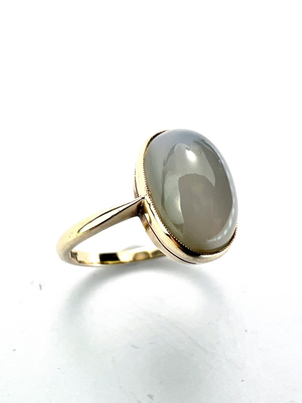 An Edwardian 9ct yellow gold solitaire ring featuring a smooth, oval grey chalcedony cabochon set in a bezel mount. View II