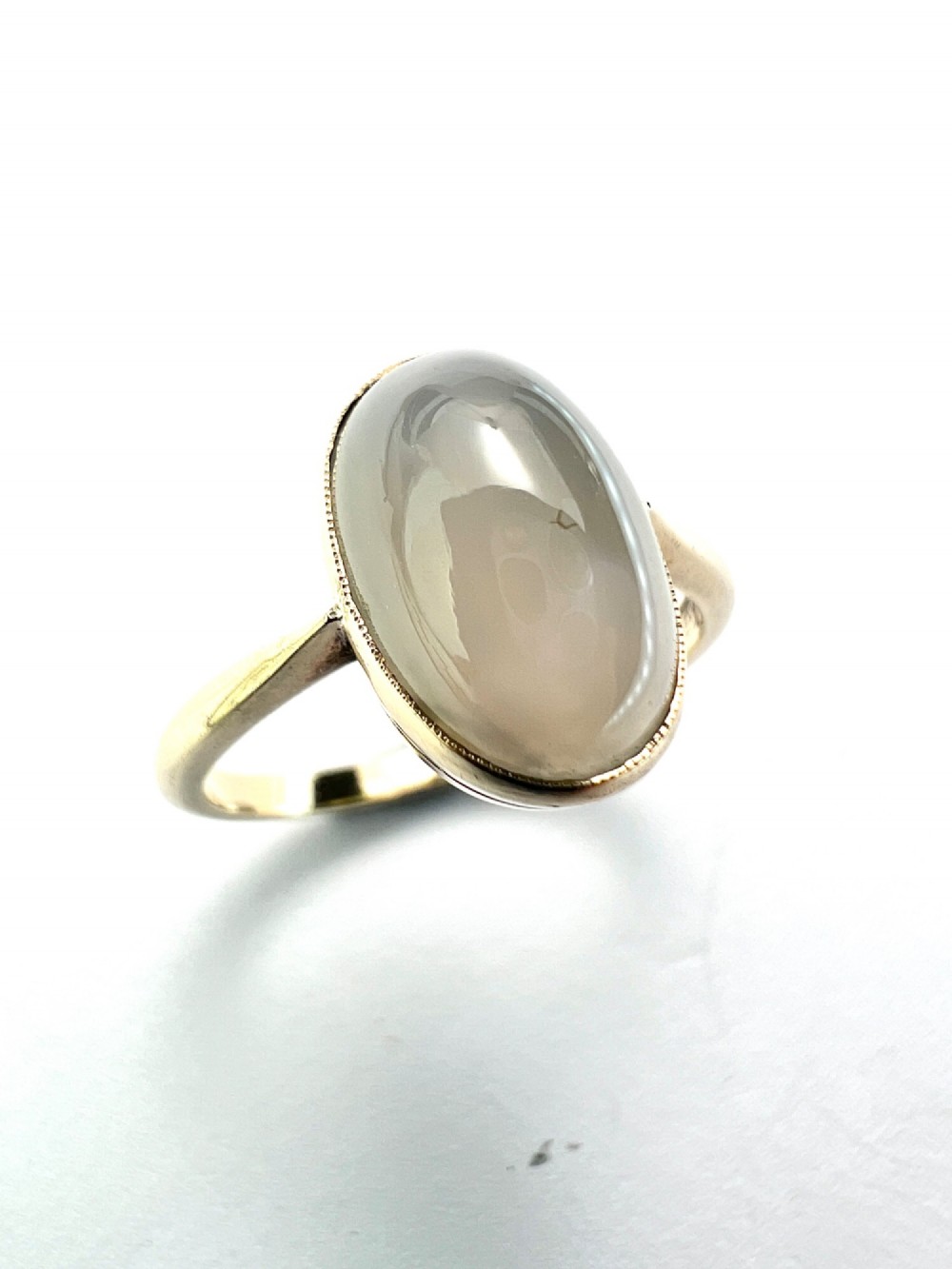 An Edwardian 9ct yellow gold solitaire ring featuring a smooth, oval grey chalcedony cabochon set in a bezel mount. View III