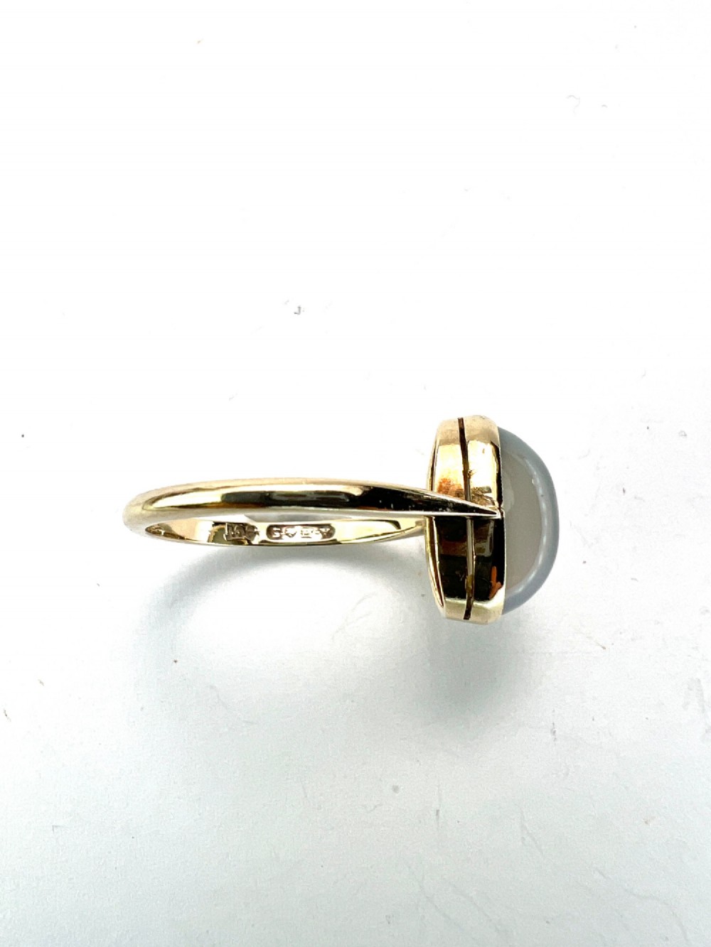 An Edwardian 9ct yellow gold solitaire ring featuring a smooth, oval grey chalcedony cabochon set in a bezel mount. View IV