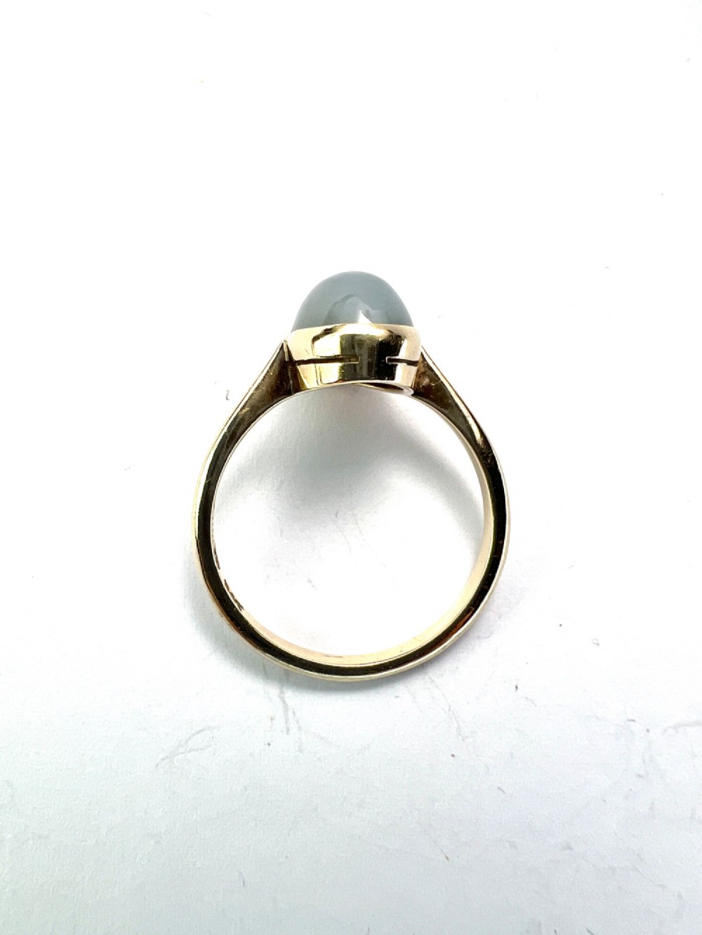 An Edwardian 9ct yellow gold solitaire ring featuring a smooth, oval grey chalcedony cabochon set in a bezel mount. View V