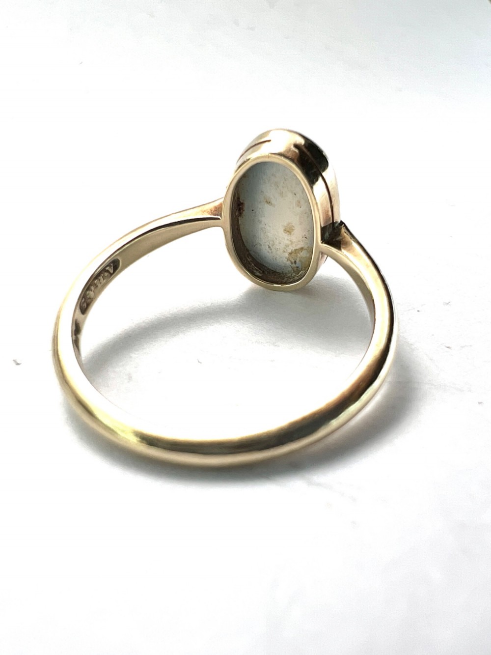 An Edwardian 9ct yellow gold solitaire ring featuring a smooth, oval grey chalcedony cabochon set in a bezel mount. View VI