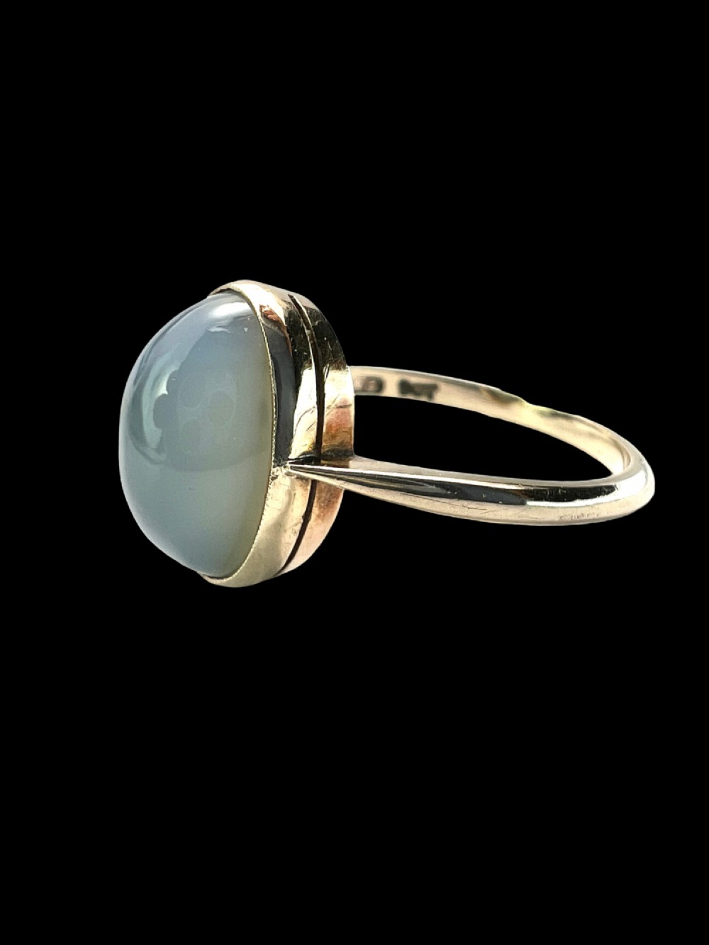 An Edwardian 9ct yellow gold solitaire ring featuring a smooth, oval grey chalcedony cabochon set in a bezel mount. View VIII