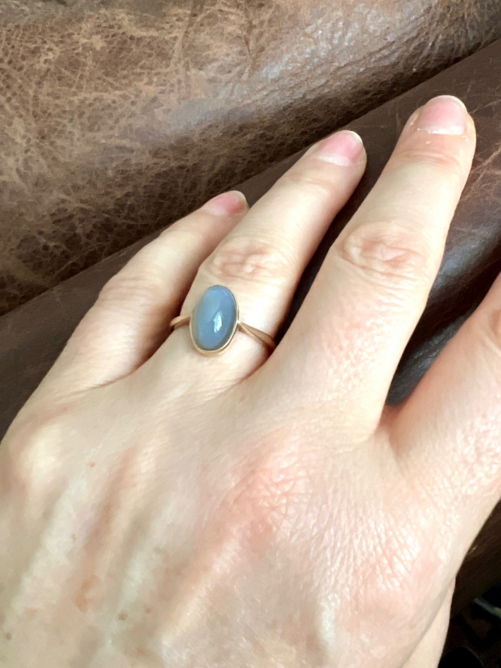 An Edwardian 9ct yellow gold solitaire ring featuring a smooth, oval grey chalcedony cabochon set in a bezel mount. View IX