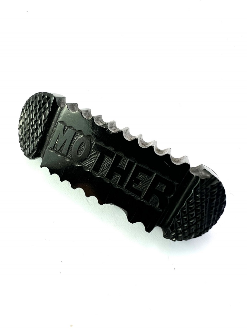 An oblong carved black Whitby jet brooch featuring the raised carved word MOTHER flanked by cross-hatched ends and notched borders. View III