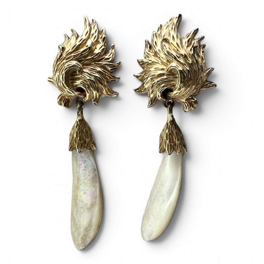 A pair of vintage gold-tone clip-on earrings featuring textured flame-like tops and hanging elongated mother-of-pearl drop pendants.