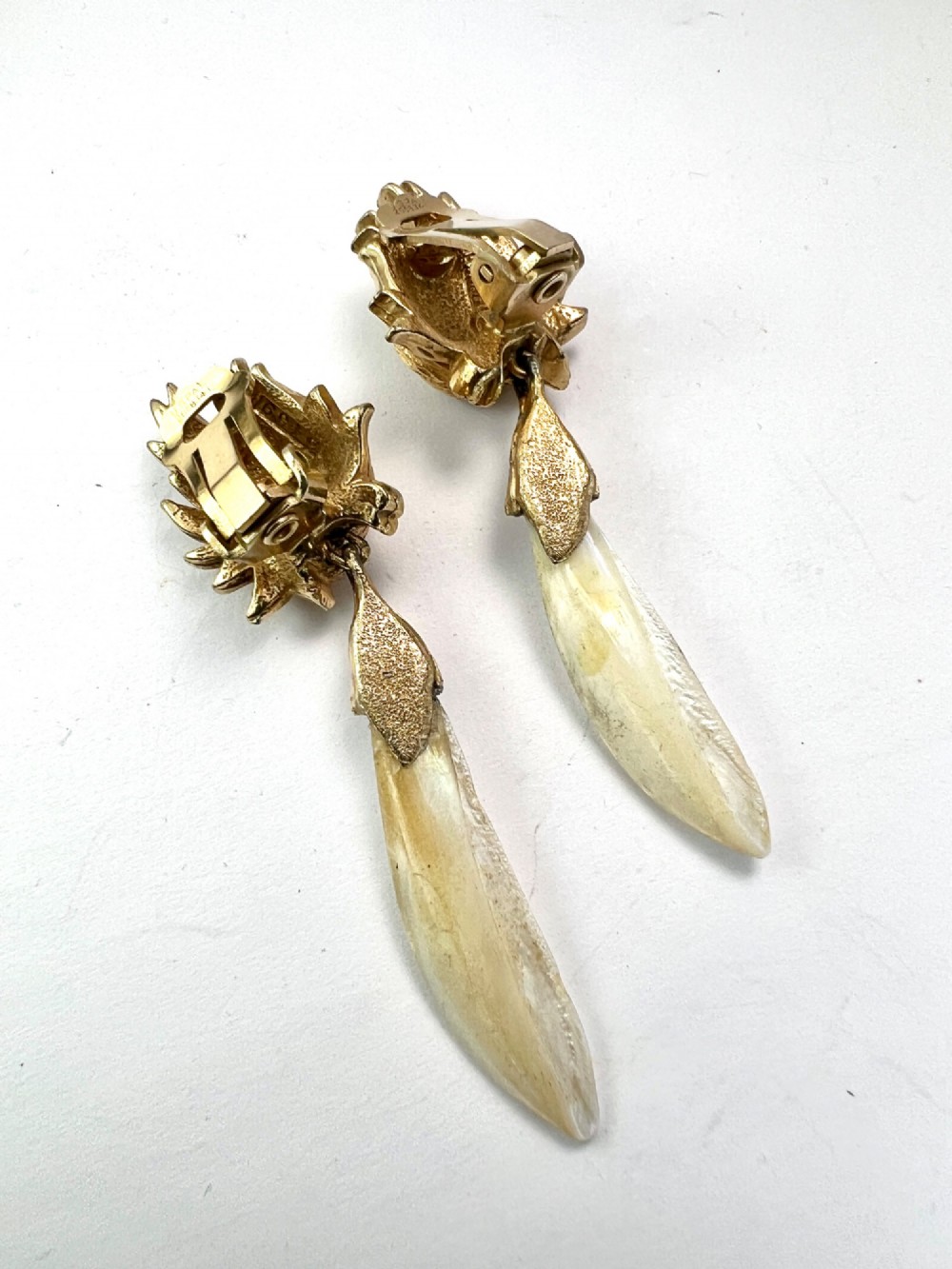 A pair of vintage gold-tone clip-on earrings featuring textured flame-like tops and hanging elongated mother-of-pearl drop pendants. View II