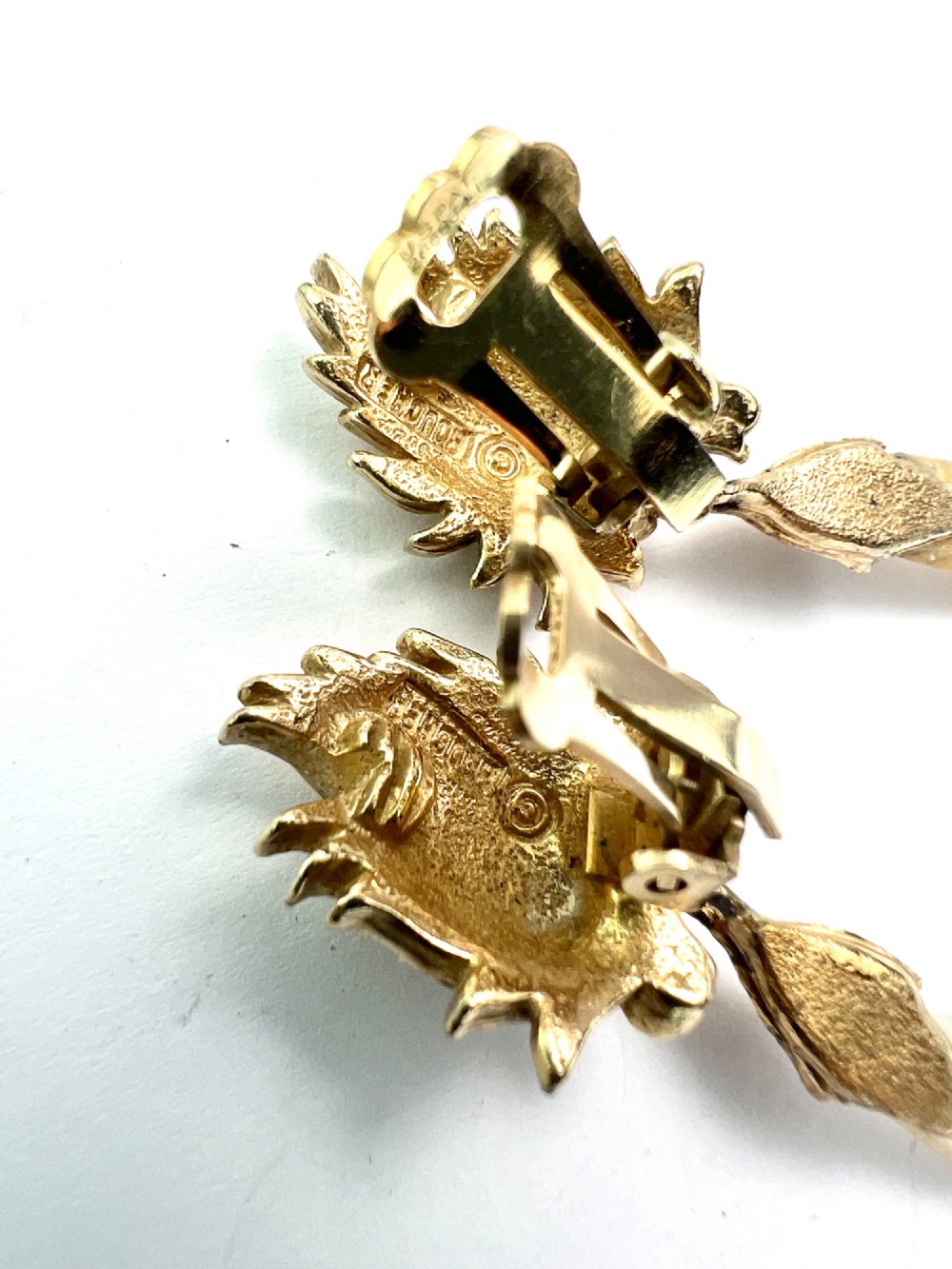A pair of vintage gold-tone clip-on earrings featuring textured flame-like tops and hanging elongated mother-of-pearl drop pendants. View III