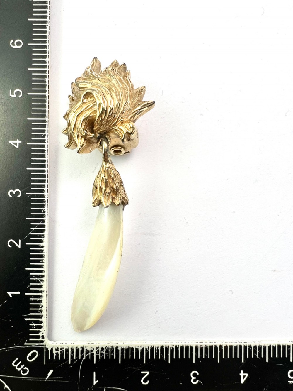 A pair of vintage gold-tone clip-on earrings featuring textured flame-like tops and hanging elongated mother-of-pearl drop pendants. View IV