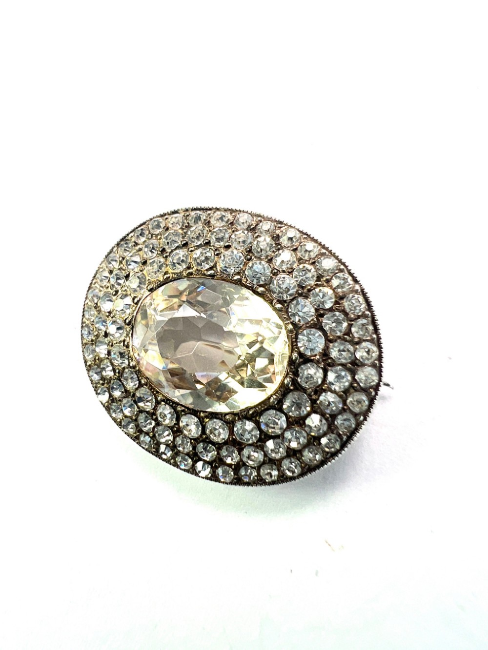 An oval Edwardian brooch featuring a large central oval paste stone bordered by multiple rows of smaller brilliant-cut paste stones in a silver mounting. View III