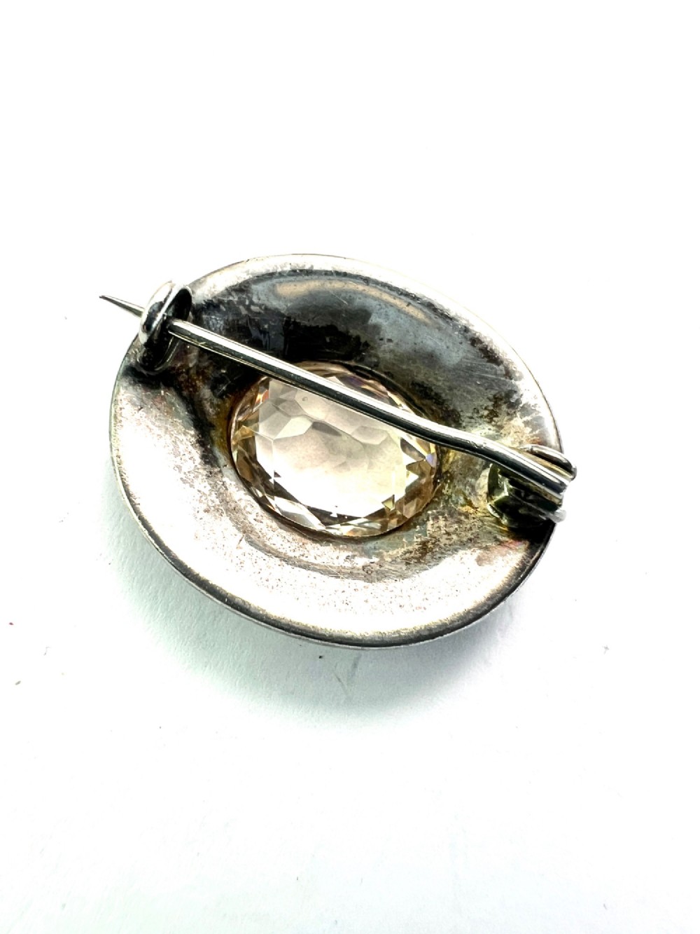 An oval Edwardian brooch featuring a large central oval paste stone bordered by multiple rows of smaller brilliant-cut paste stones in a silver mounting. View IV
