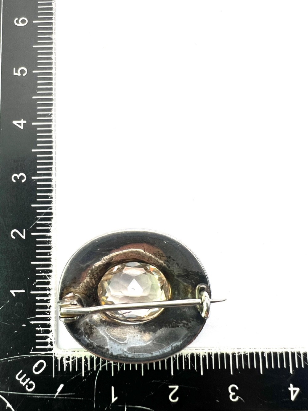 An oval Edwardian brooch featuring a large central oval paste stone bordered by multiple rows of smaller brilliant-cut paste stones in a silver mounting. View V