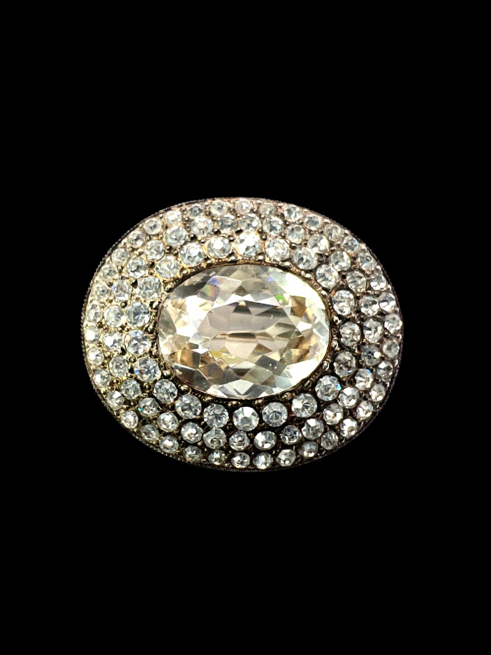 An oval Edwardian brooch featuring a large central oval paste stone bordered by multiple rows of smaller brilliant-cut paste stones in a silver mounting. View VI