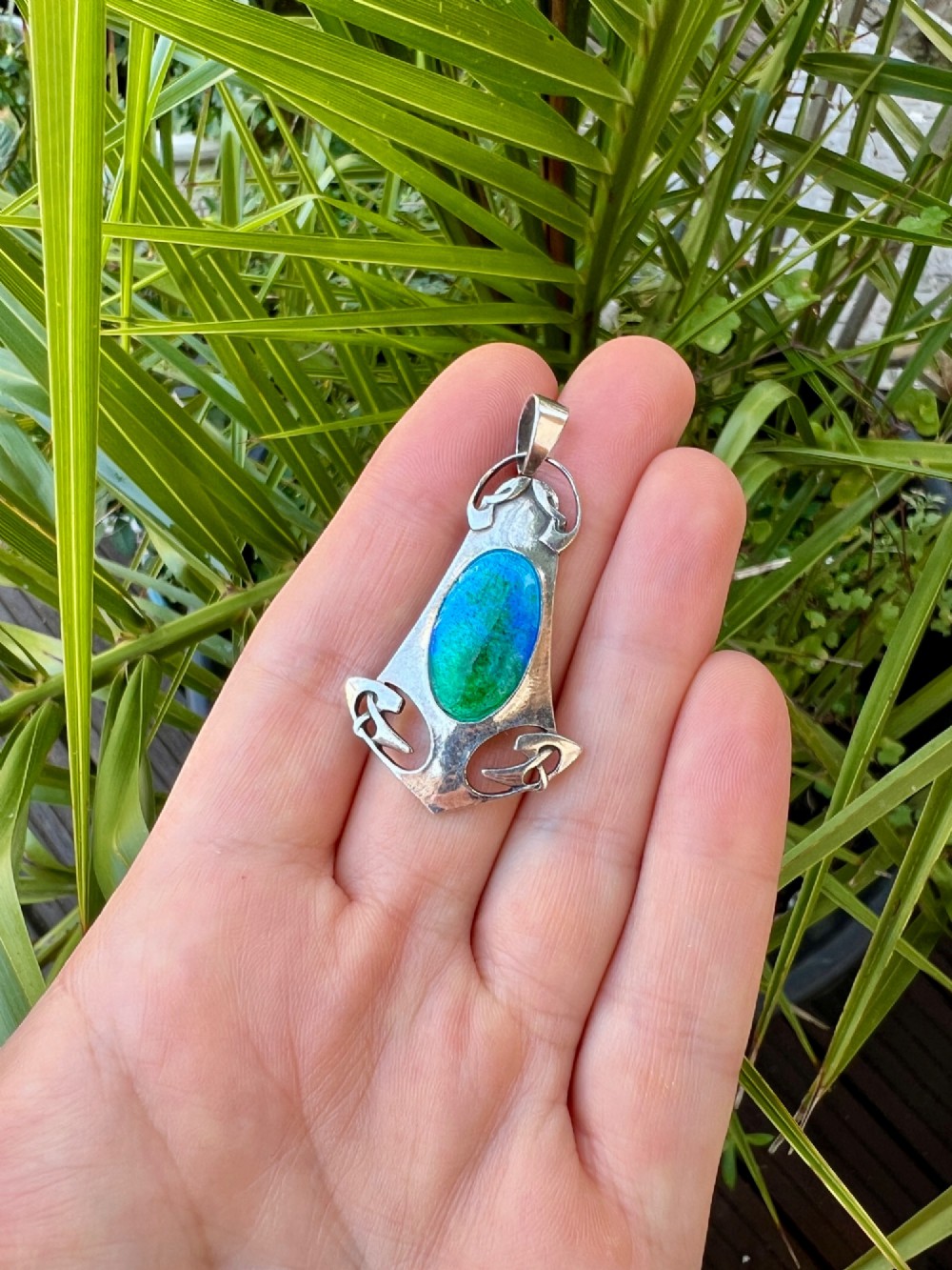 A silver Arts and Crafts style openwork pendant featuring stylised Celtic knots around a central oval blue and green enamel insert. View VII