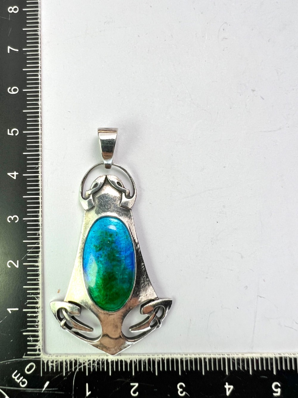 A silver Arts and Crafts style openwork pendant featuring stylised Celtic knots around a central oval blue and green enamel insert. View IX