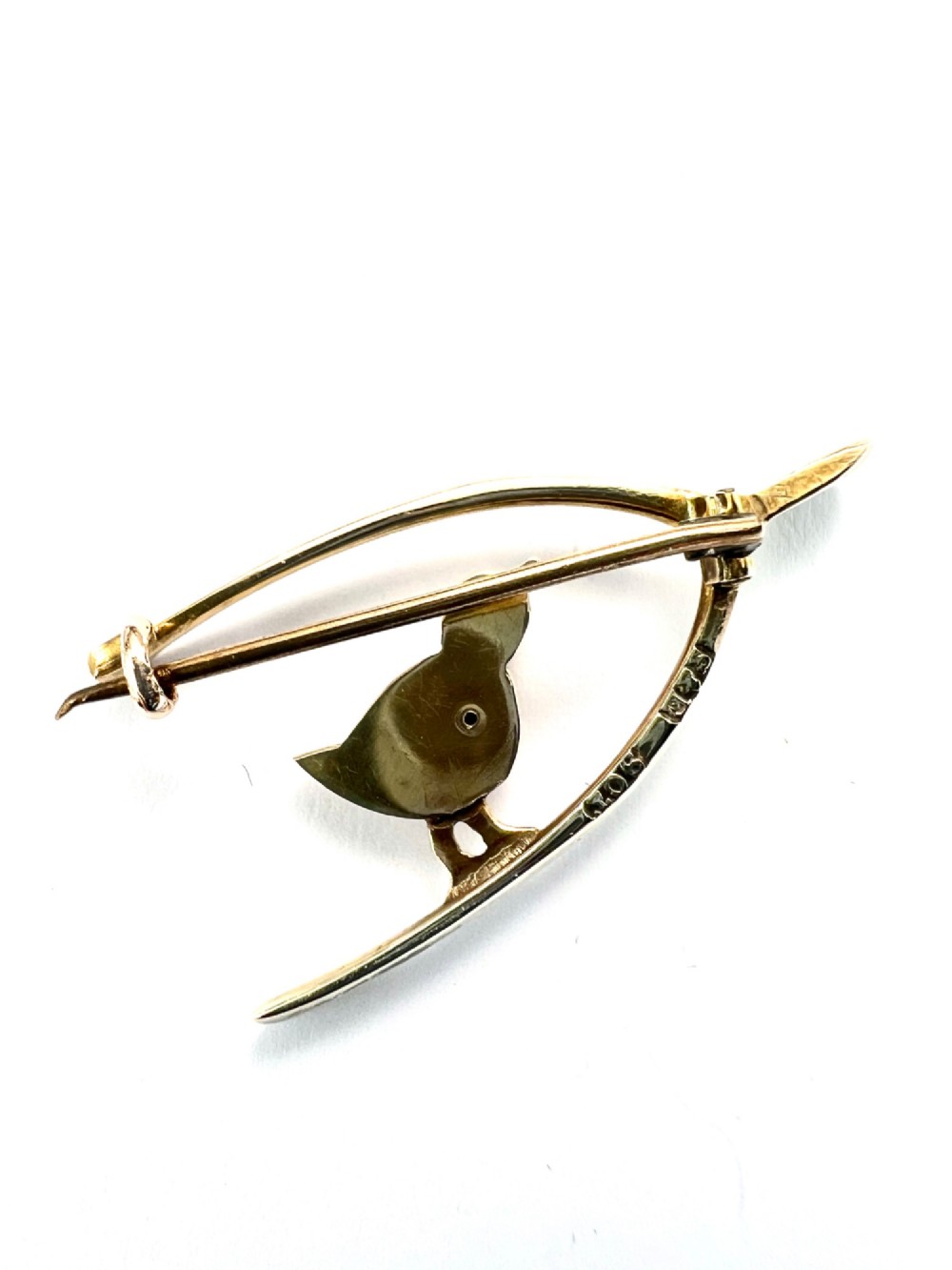 An Edwardian 9ct gold wishbone brooch featuring an engraved chick with a small diamond eye. View IV