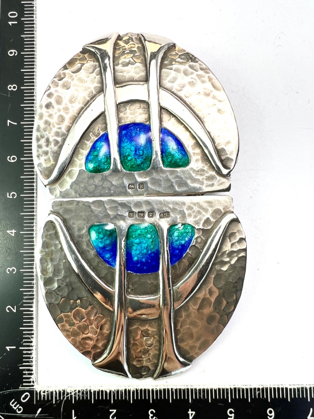A two-part Art Nouveau sterling silver belt buckle featuring hand-hammered oval surfaces inlaid with vibrant blue and green enamelling and hallmarked in the centre. View IX