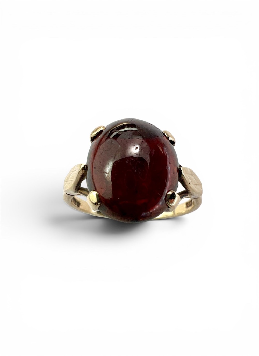 An overhead view of a vintage 9ct gold ring featuring a large oval cabochon-cut garnet held by four claw settings. View II