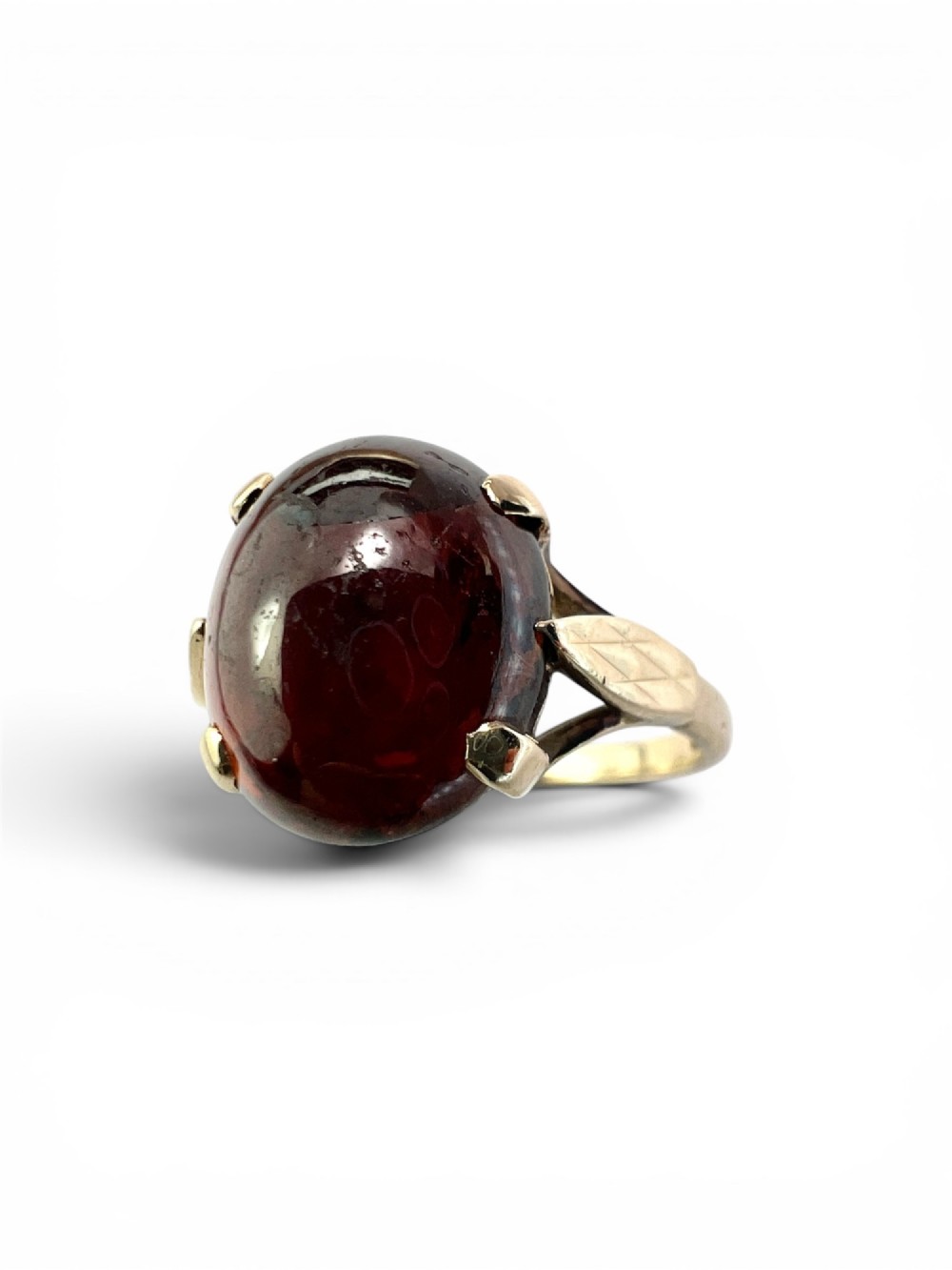 An overhead view of a vintage 9ct gold ring featuring a large oval cabochon-cut garnet held by four claw settings. View III