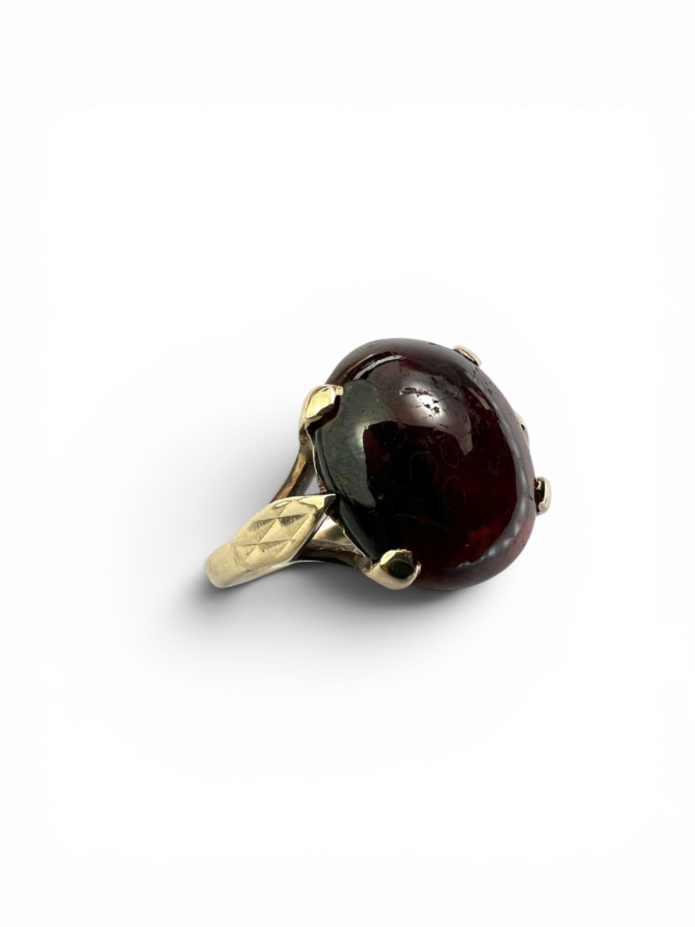 An overhead view of a vintage 9ct gold ring featuring a large oval cabochon-cut garnet held by four claw settings. View IV