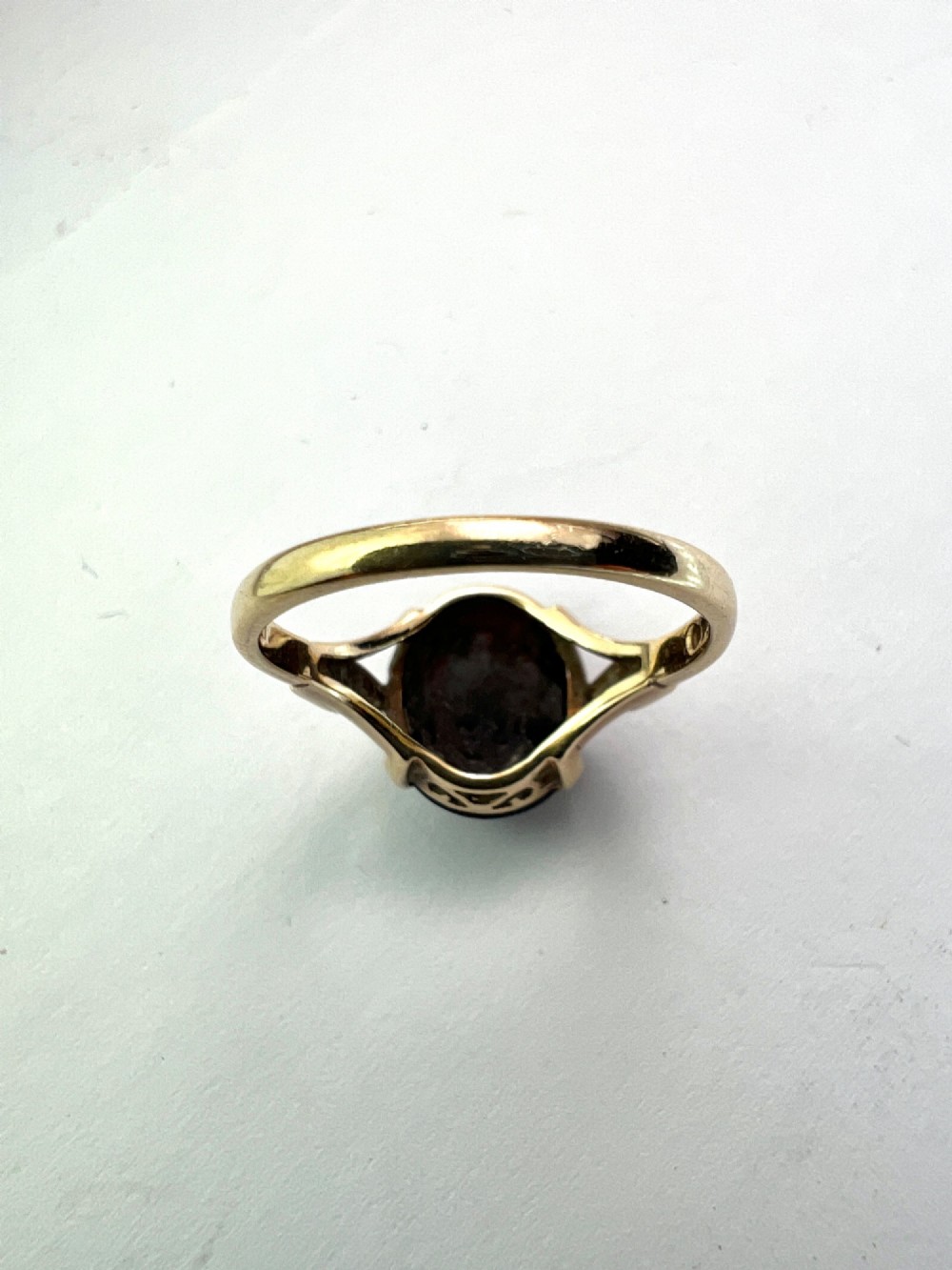 An overhead view of a vintage 9ct gold ring featuring a large oval cabochon-cut garnet held by four claw settings. View VI