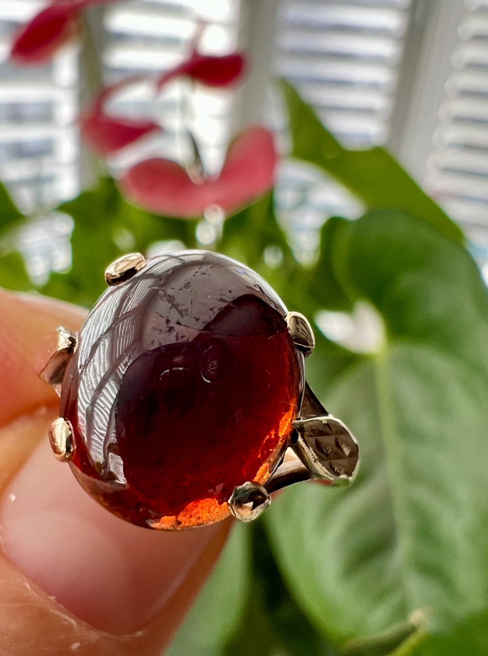 An overhead view of a vintage 9ct gold ring featuring a large oval cabochon-cut garnet held by four claw settings. View IX