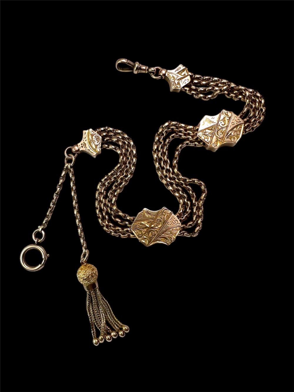 An antique 9ct yellow gold Albertina watch chain featuring four strands, decorative engraved slides, a swivel clasp, and a dangling tassel. View II