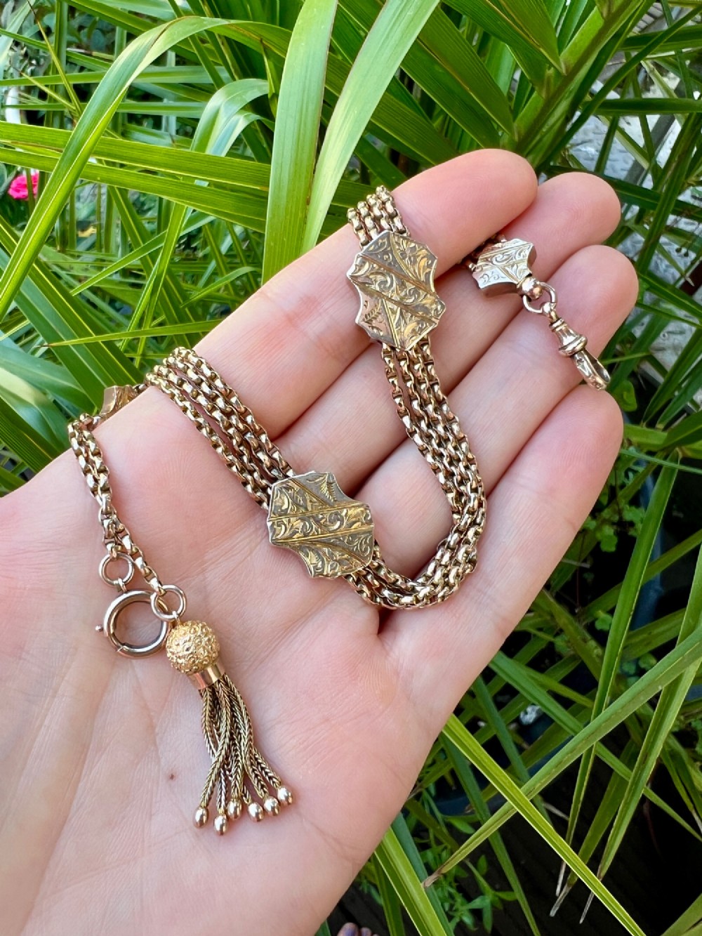 An antique 9ct yellow gold Albertina watch chain featuring four strands, decorative engraved slides, a swivel clasp, and a dangling tassel. View IV