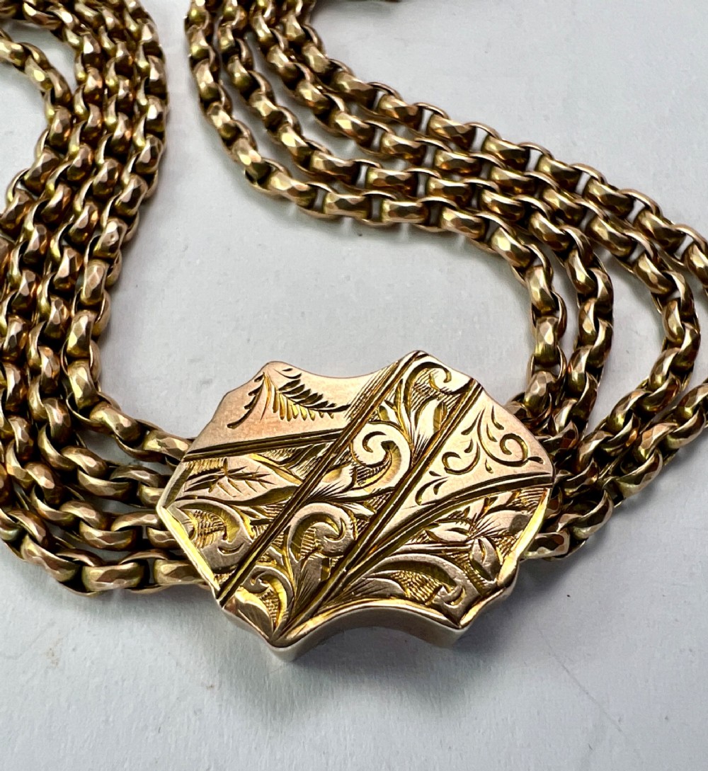 An antique 9ct yellow gold Albertina watch chain featuring four strands, decorative engraved slides, a swivel clasp, and a dangling tassel. View VII