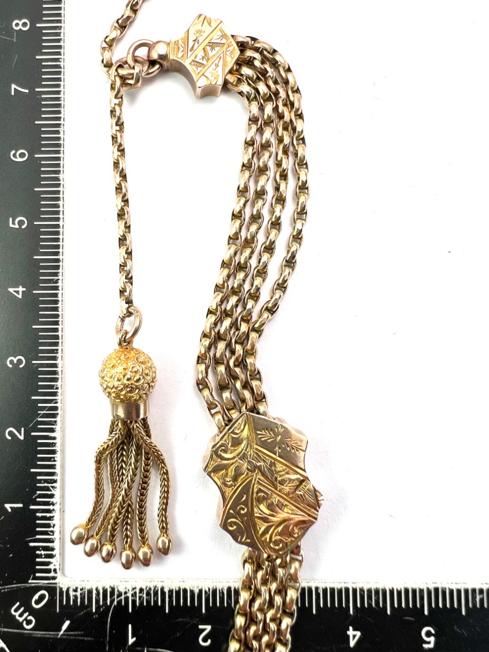 An antique 9ct yellow gold Albertina watch chain featuring four strands, decorative engraved slides, a swivel clasp, and a dangling tassel. View IX