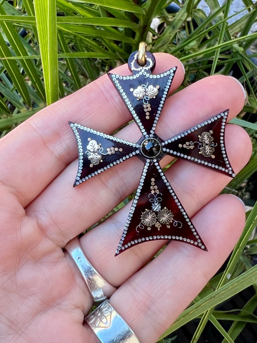 A dark tortoiseshell cross pattee pendant decorated with gold and silver pique inlay of foliate motifs and bordered by silver pinwork with a central black cabochon. View VIII