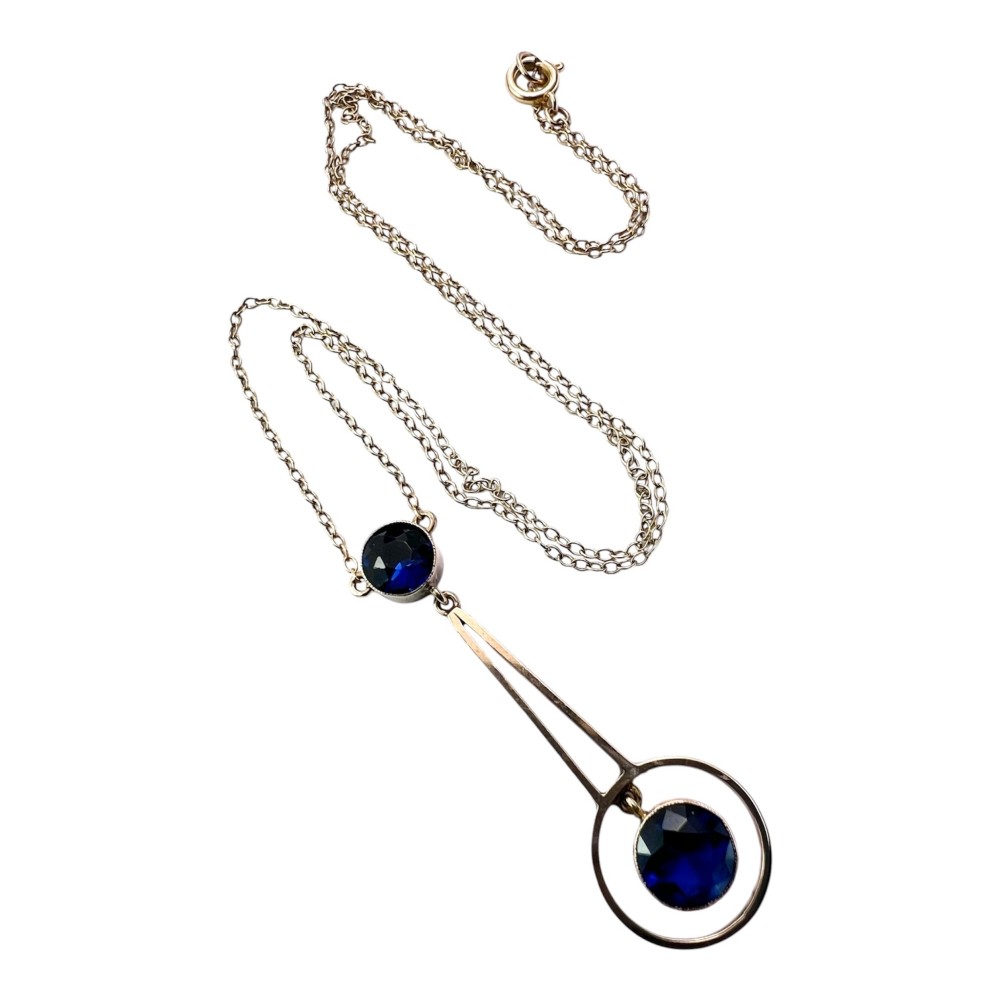 An Edwardian 9ct gold fine chain necklace featuring a geometric drop pendant set with two faceted dark blue paste stones.