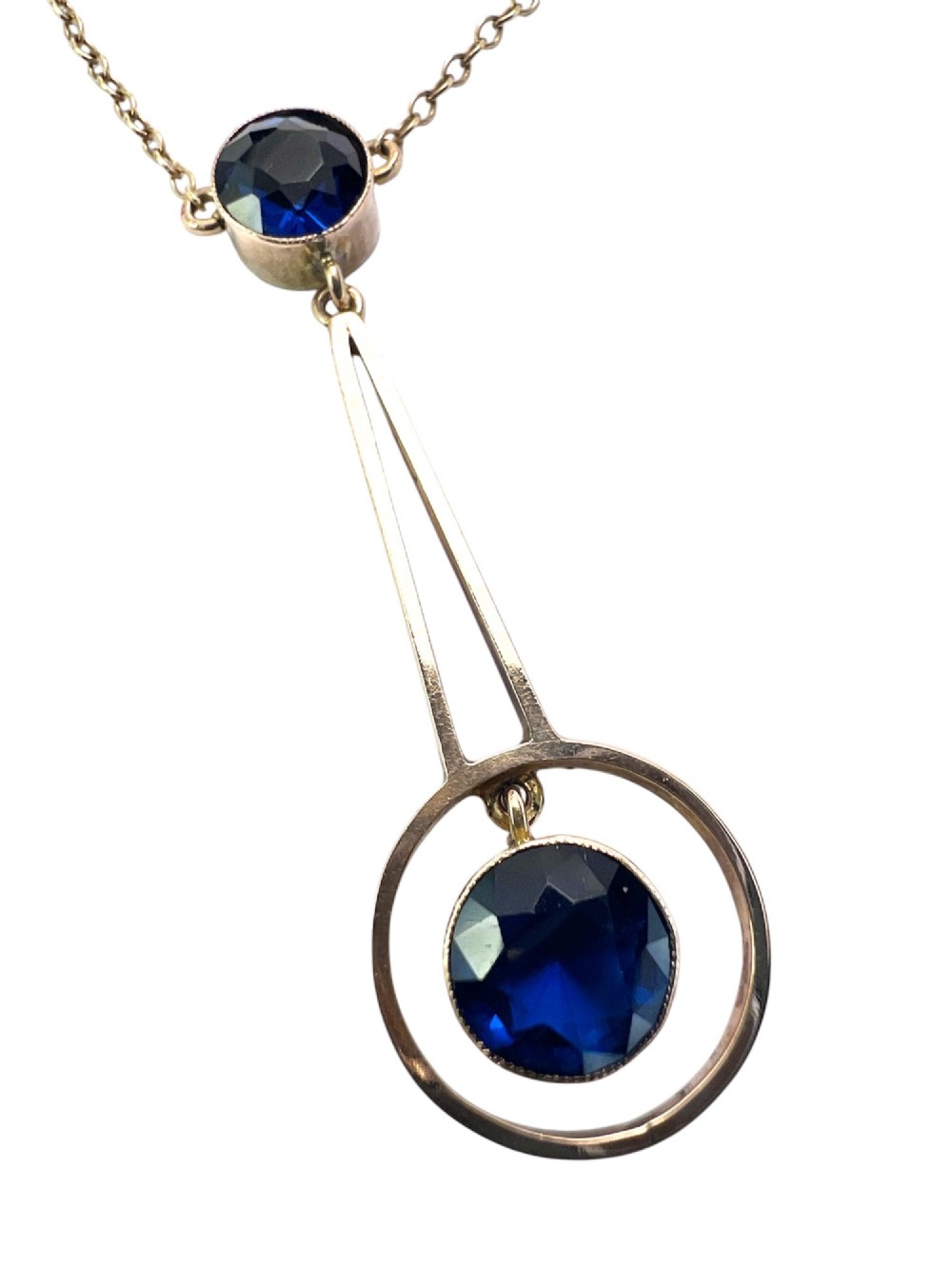 An Edwardian 9ct gold fine chain necklace featuring a geometric drop pendant set with two faceted dark blue paste stones. View II