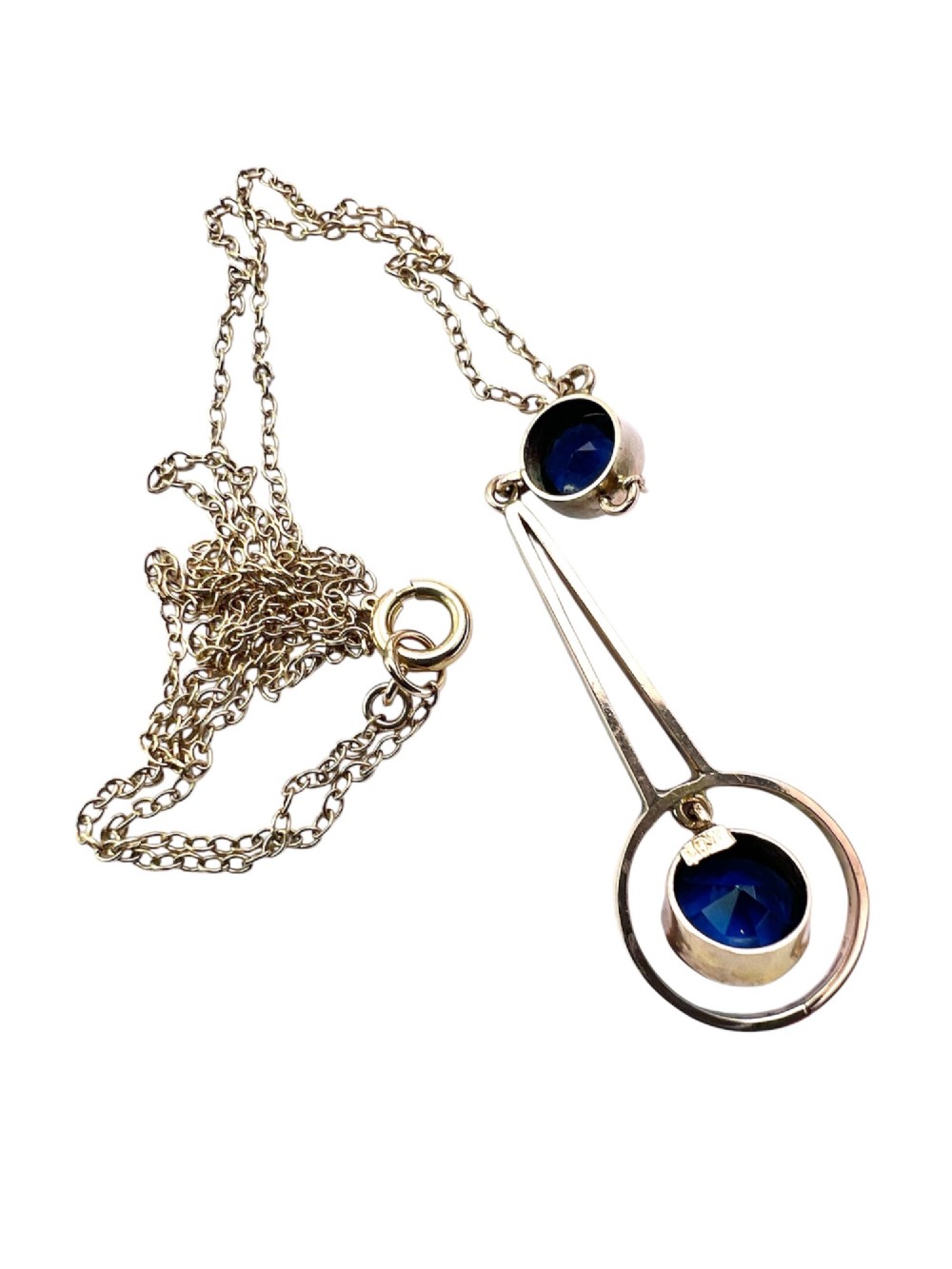 An Edwardian 9ct gold fine chain necklace featuring a geometric drop pendant set with two faceted dark blue paste stones. View IV