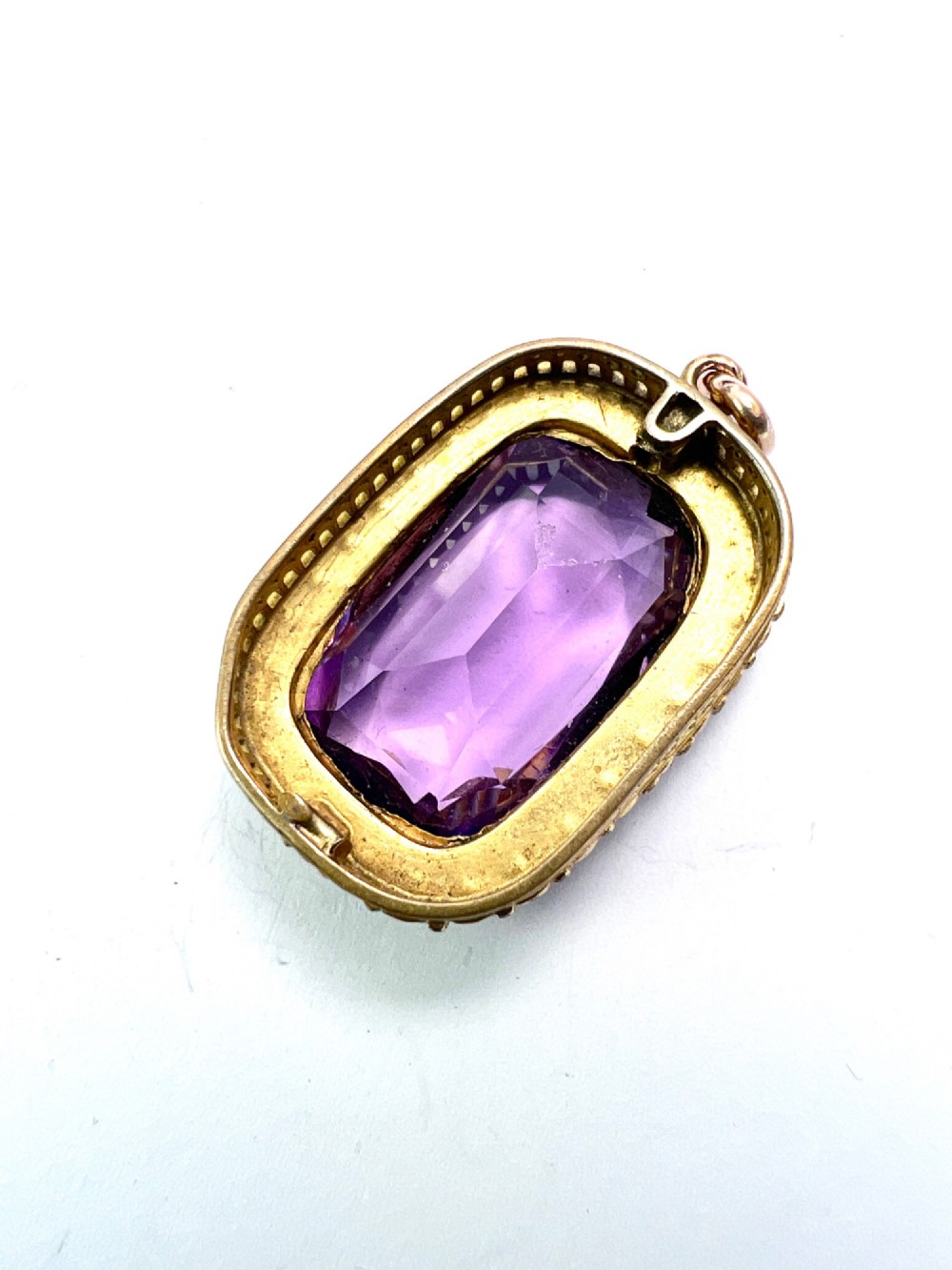 A Victorian rectangular cushion-cut purple paste stone pendant surrounded by a halo of small white seed pearls in a gold mount. View IV