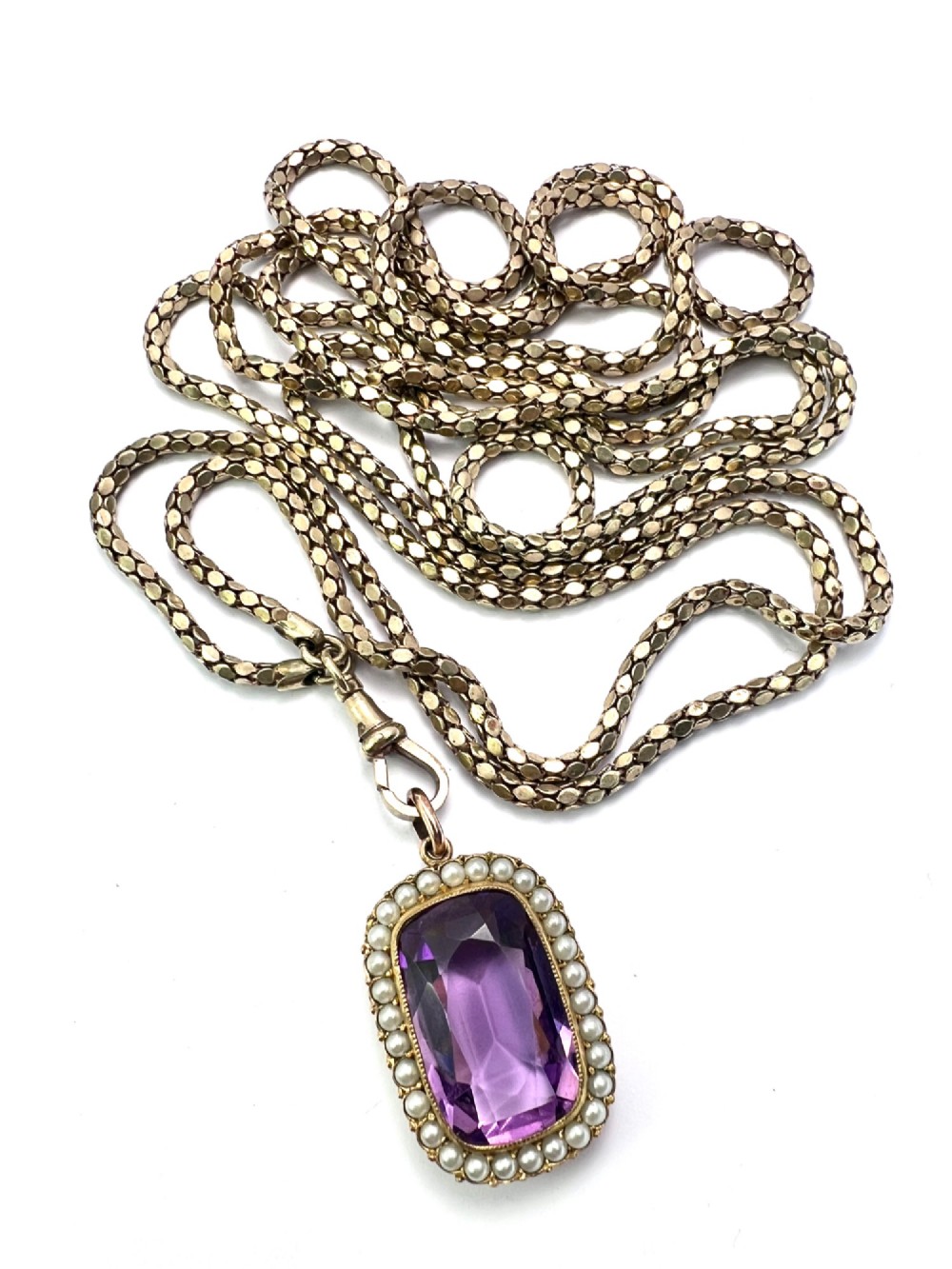 A Victorian rectangular cushion-cut purple paste stone pendant surrounded by a halo of small white seed pearls in a gold mount. View VIII