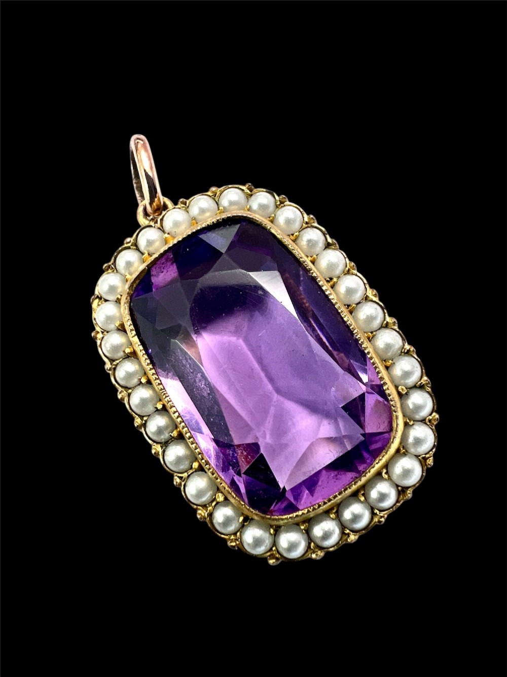 A Victorian rectangular cushion-cut purple paste stone pendant surrounded by a halo of small white seed pearls in a gold mount. View IX