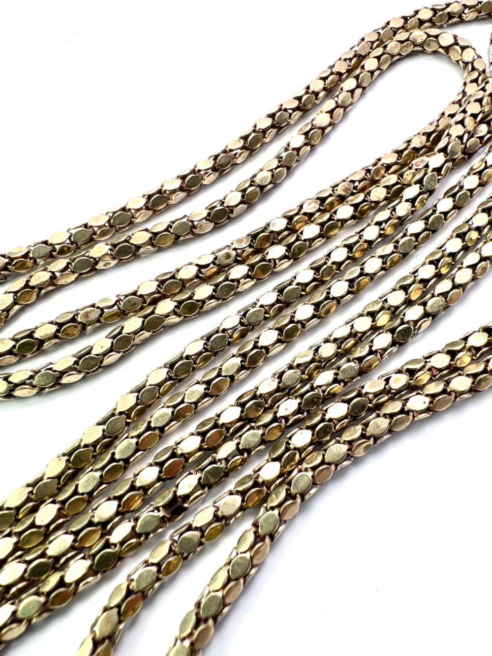 A long yellow gold longuard chain featuring faceted textured links and an Albert swivel clip at the end on a white surface. View III