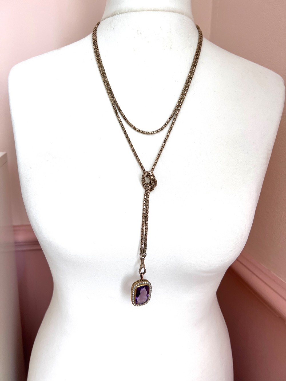 A long yellow gold longuard chain featuring faceted textured links and an Albert swivel clip at the end on a white surface. View VII