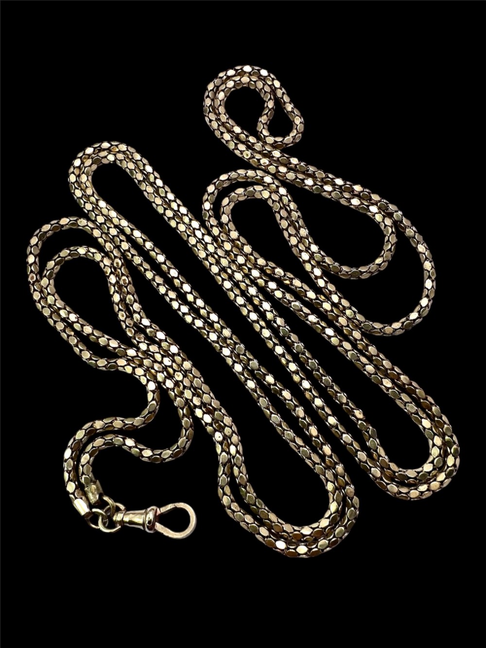 A long yellow gold longuard chain featuring faceted textured links and an Albert swivel clip at the end on a white surface. View IX