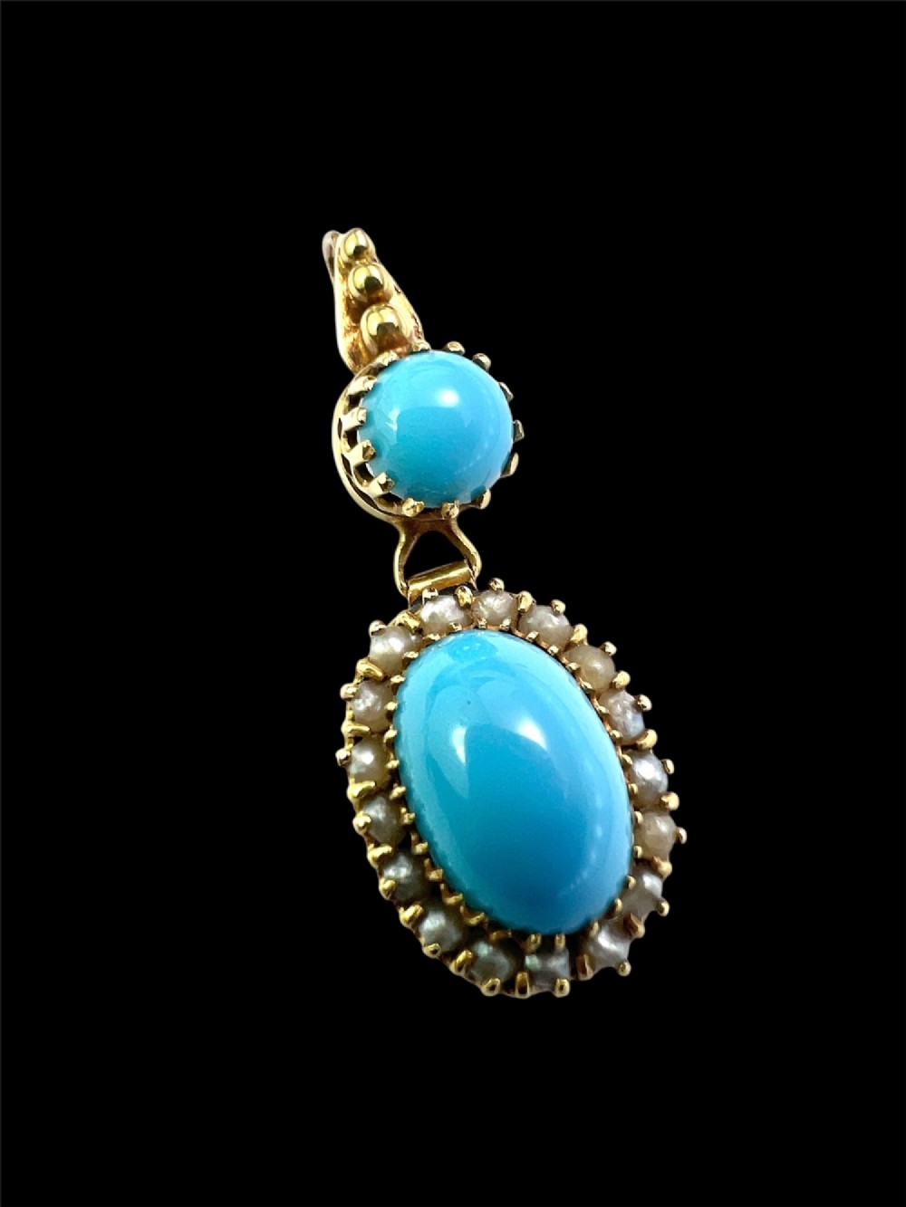 A Victorian yellow gold drop pendant featuring an oval turquoise cabochon framed by a seed pearl halo, hanging below a smaller round turquoise stone. View II