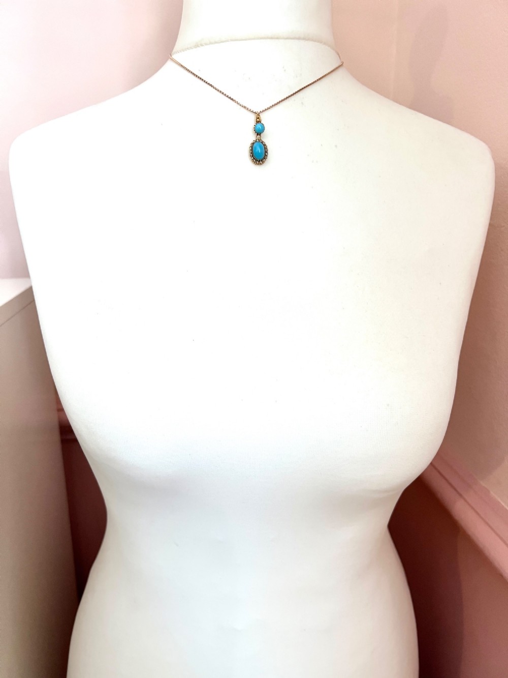 A Victorian yellow gold drop pendant featuring an oval turquoise cabochon framed by a seed pearl halo, hanging below a smaller round turquoise stone. View VII