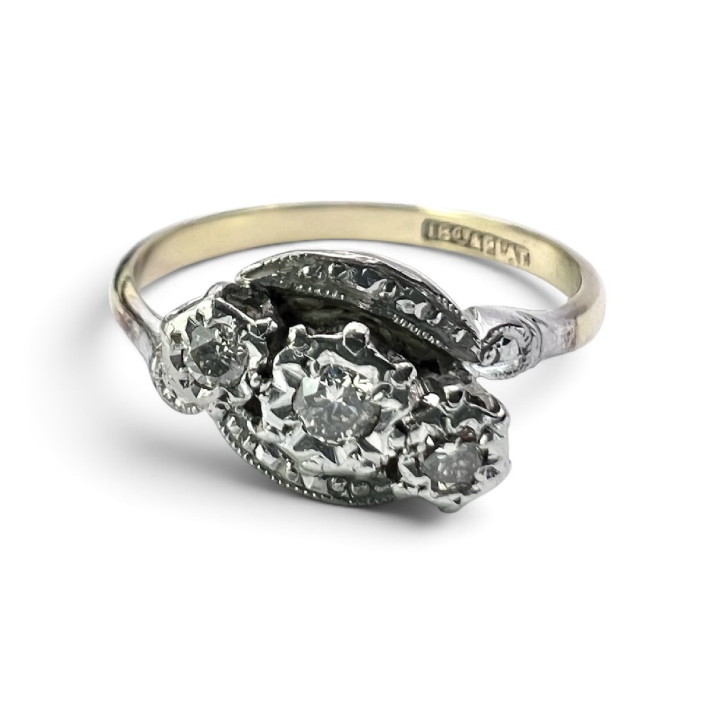 A vintage 18ct yellow gold and platinum ring featuring three small diamonds set in an ornate crossover mount with millegrain detailing.