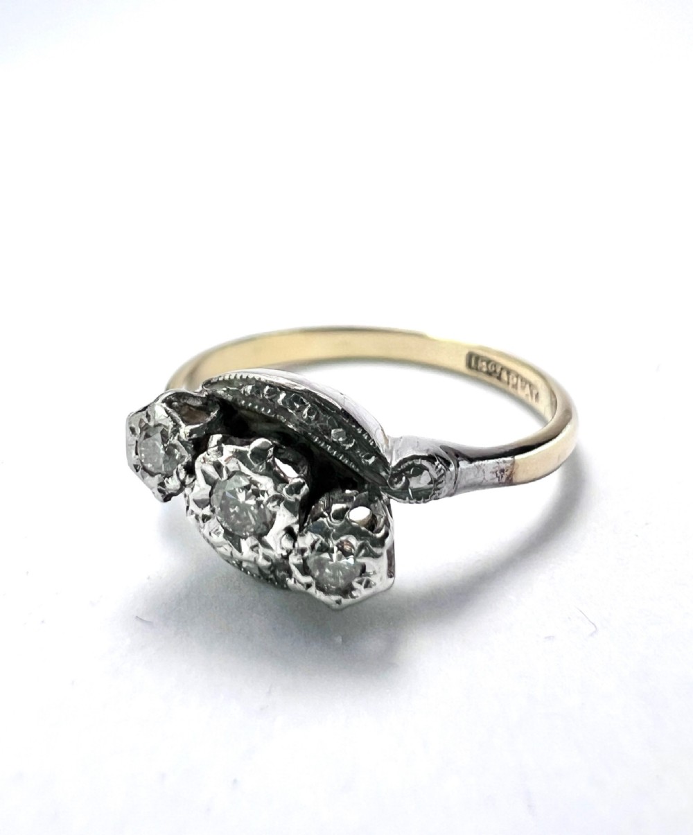 A vintage 18ct yellow gold and platinum ring featuring three small diamonds set in an ornate crossover mount with millegrain detailing. View IV
