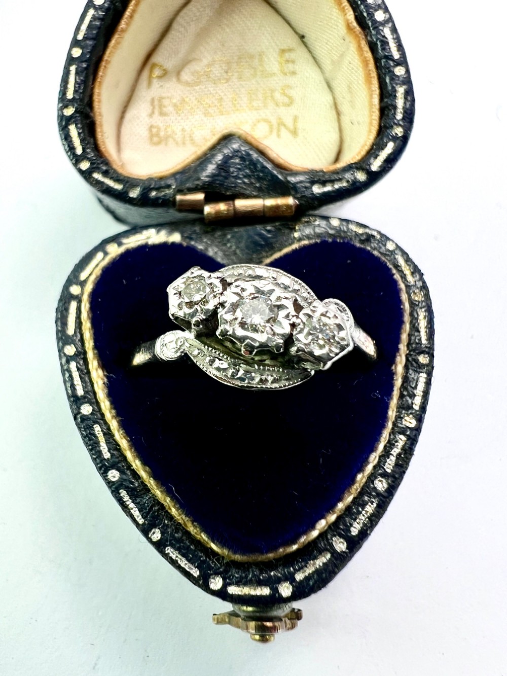 A vintage 18ct yellow gold and platinum ring featuring three small diamonds set in an ornate crossover mount with millegrain detailing. View VI