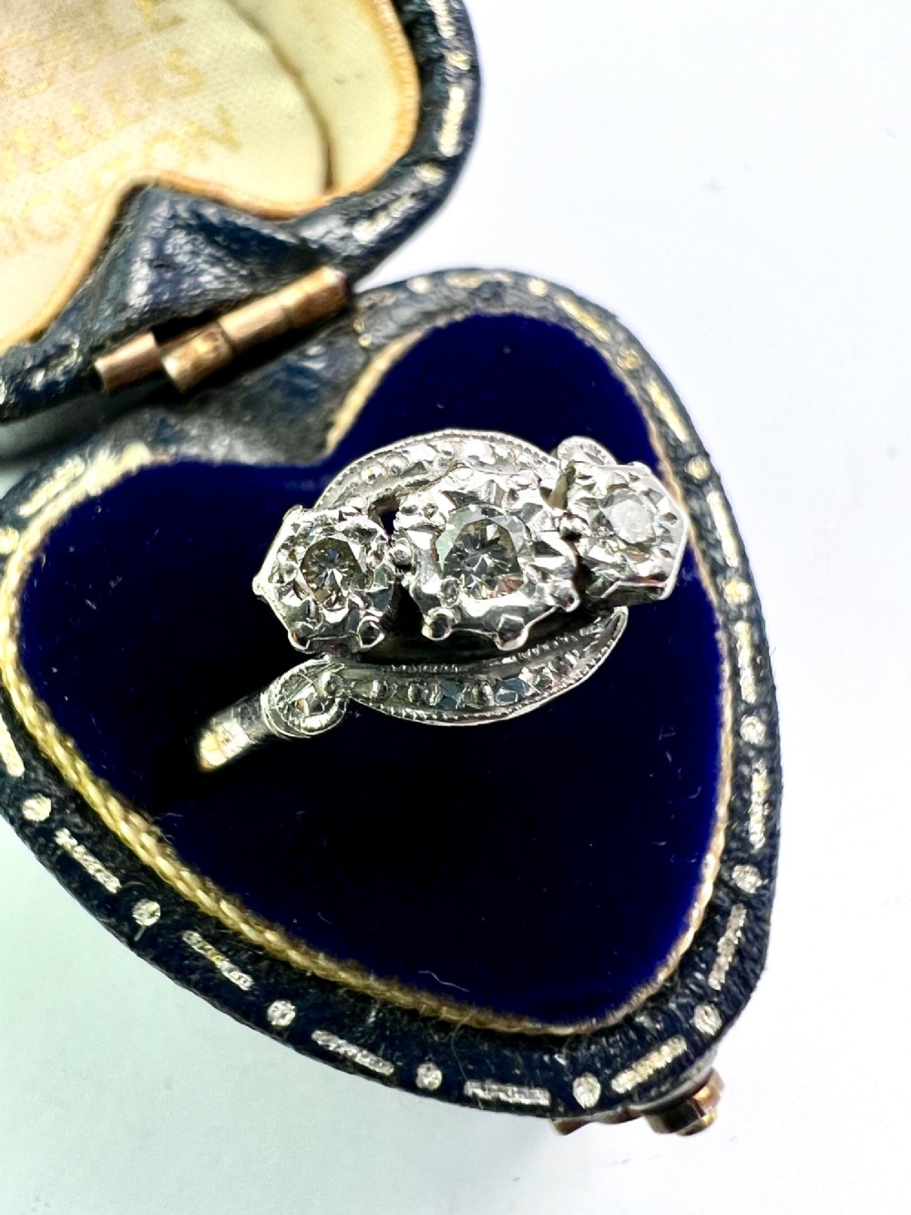 A vintage 18ct yellow gold and platinum ring featuring three small diamonds set in an ornate crossover mount with millegrain detailing. View VII