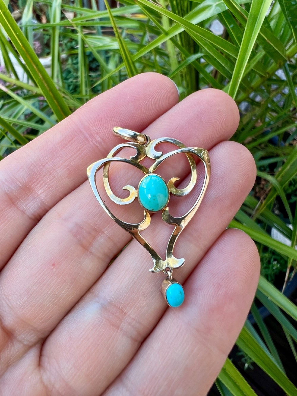 An Art Nouveau 9ct yellow gold openwork heart-shaped pendant set with a central turquoise cabochon and a dangling oval turquoise stone. View V