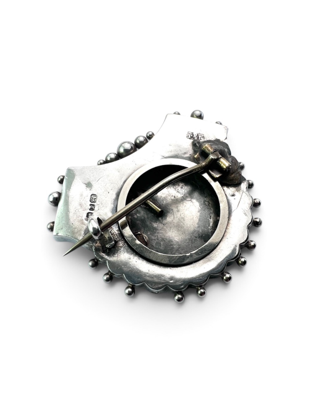 A Victorian silver shield-shaped brooch decorated with applied rose gold flowers, hand engraving, and a beaded outer rim. View II